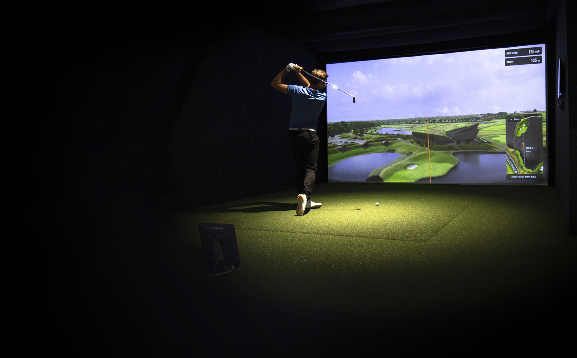 Man checking Trackman app in indoor golf simulator